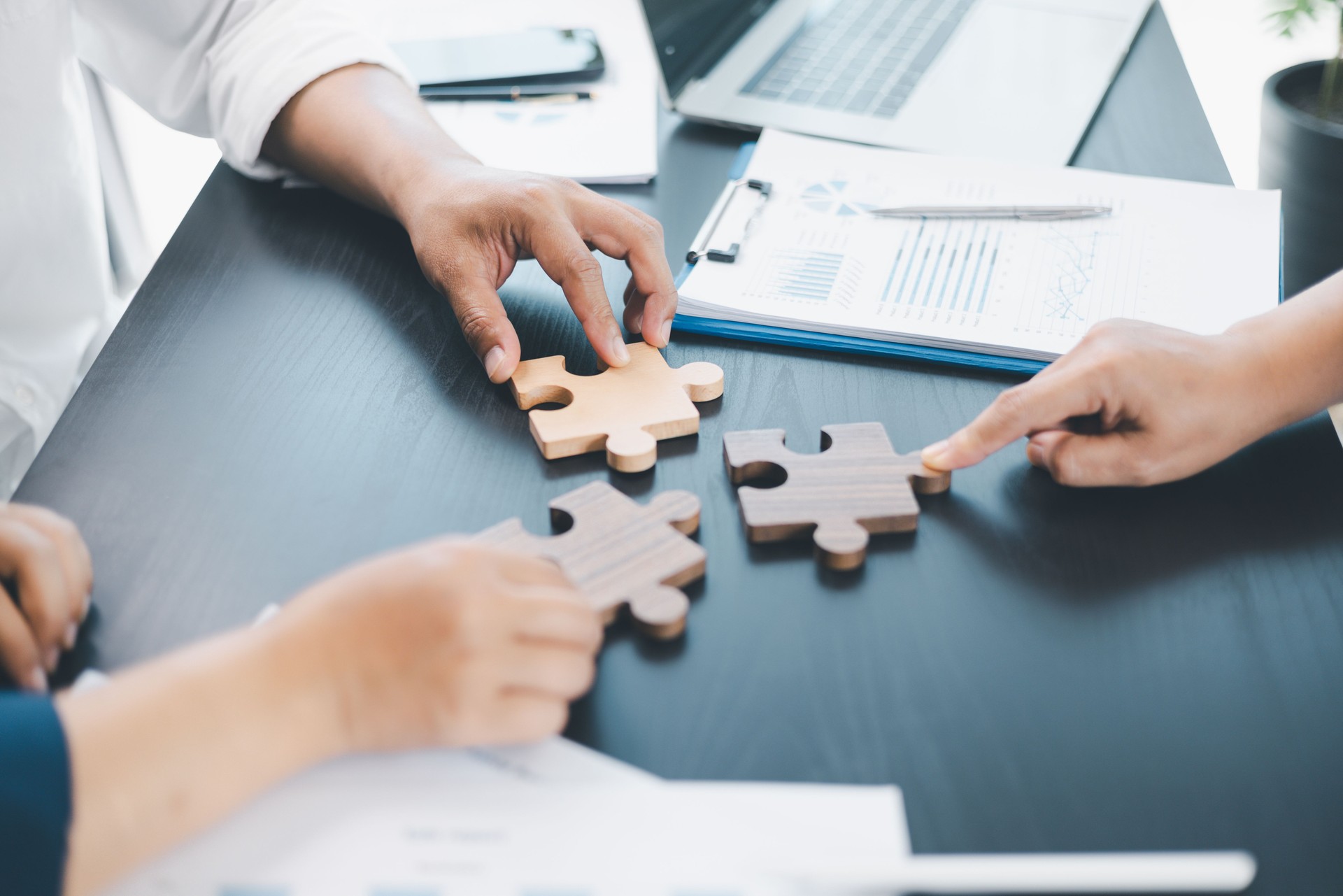 Business teamwork concept with people holding wooden puzzle pieces together, symbol of collaboration, strategy, problem solving, partnership and corporate success in modern office. business teamwork.